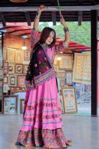 Woman in vibrant traditional Indian attire performing a festive dance, suitable for a Navratri jewelry editorial
