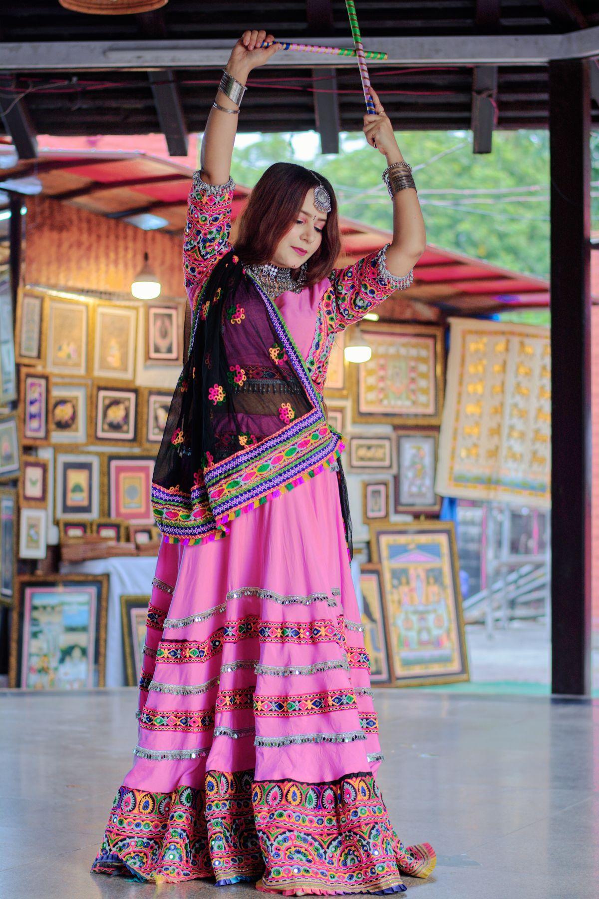 Woman in vibrant traditional Indian attire performing a festive dance, suitable for a Navratri jewelry editorial